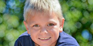 a young boy with blonde hair and a blue shirt